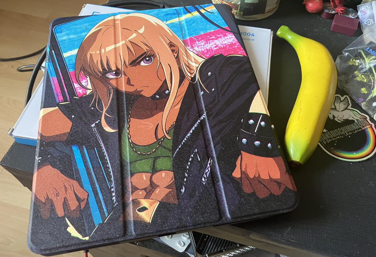 Front side of the cover with my illustration of the junker boi leaning against a broken vending machine featured on it. Banana for scale next to it.