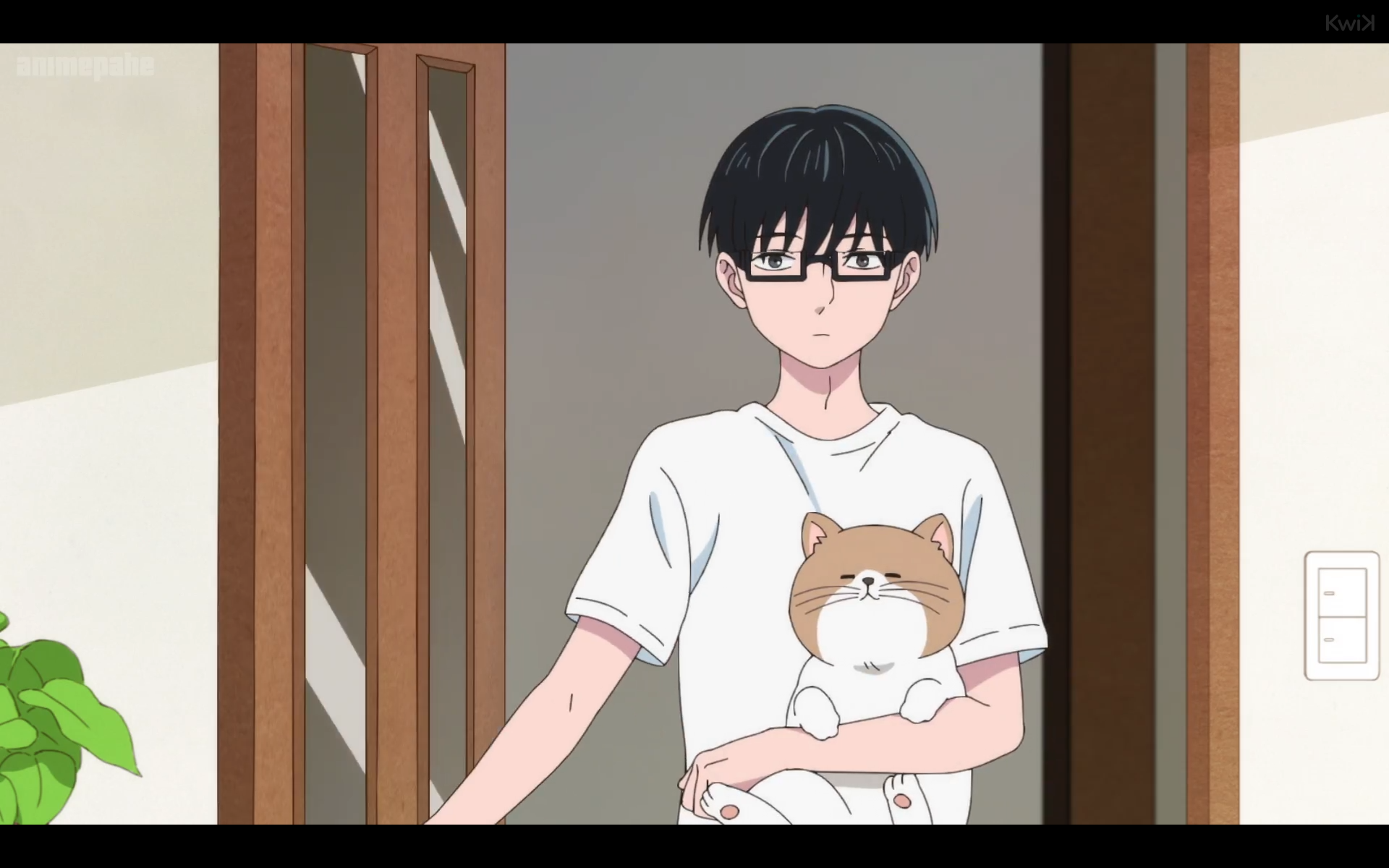same anime. now the cat is being held by his owner, a boy with dark hair and square glasses, wearing a white t-shirt