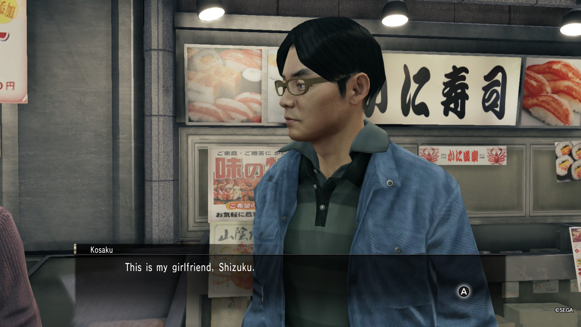 A screenshot of Yakuza 0: Director's Cut for the Switch 2. The only person in frame is a man wearing a green striped shirt and a blue jacket looking towards the left. His name is Kosaku as shown in a dialog box and says the following: "This is my girlfriend, Shizuku".